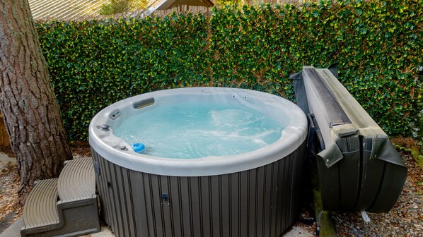 A hot tub with a cover, a step, and a chair. - Wildcat Lodge - couples retreat for two with a hot tub (Boat of Garten)