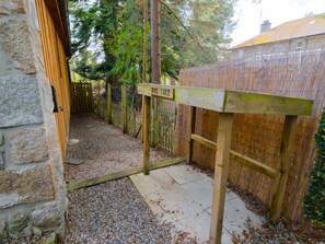 A wooden gate with a sign, a stone wall, and a gravel path leading to a building. - Wildcat Lodge - couples retreat for two with a hot tub (Boat of Garten)
