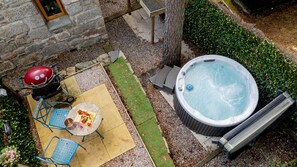 En uteplats med ett bubbelbad, en grill och ett bord med en fat med frukt.