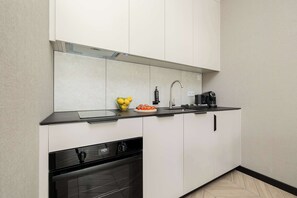 Eine moderne Küche mit schwarzem Arbeitsplatz, Spüle aus Edelstahl und Geschirrspüler.