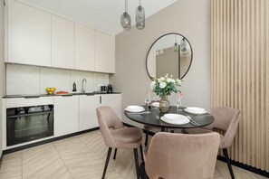 Eine moderne Küche mit weißen Schränken, einer schwarzen Arbeitsplatte und einem eingebauten Backofen.