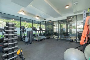 Une salle de sport équipée de tapis de course, de vélos d’exercice et d’appareils de musculation.