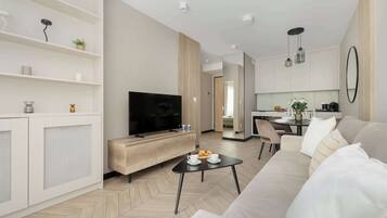 Ein modernes Wohnzimmer mit Fernseher, Sofa, Couchtisch und einem Essbereich mit Tisch und Stühlen.