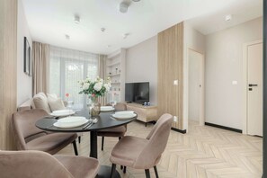 Un salon moderne comprenant un coin repas, un téléviseur à écran plat et une bibliothèque.