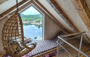 A room with a hanging chair, a cushioned bench, and a view of a lake through a large window. - 5 bedroom lovely home in Urangsvåg (Urangsvåg)