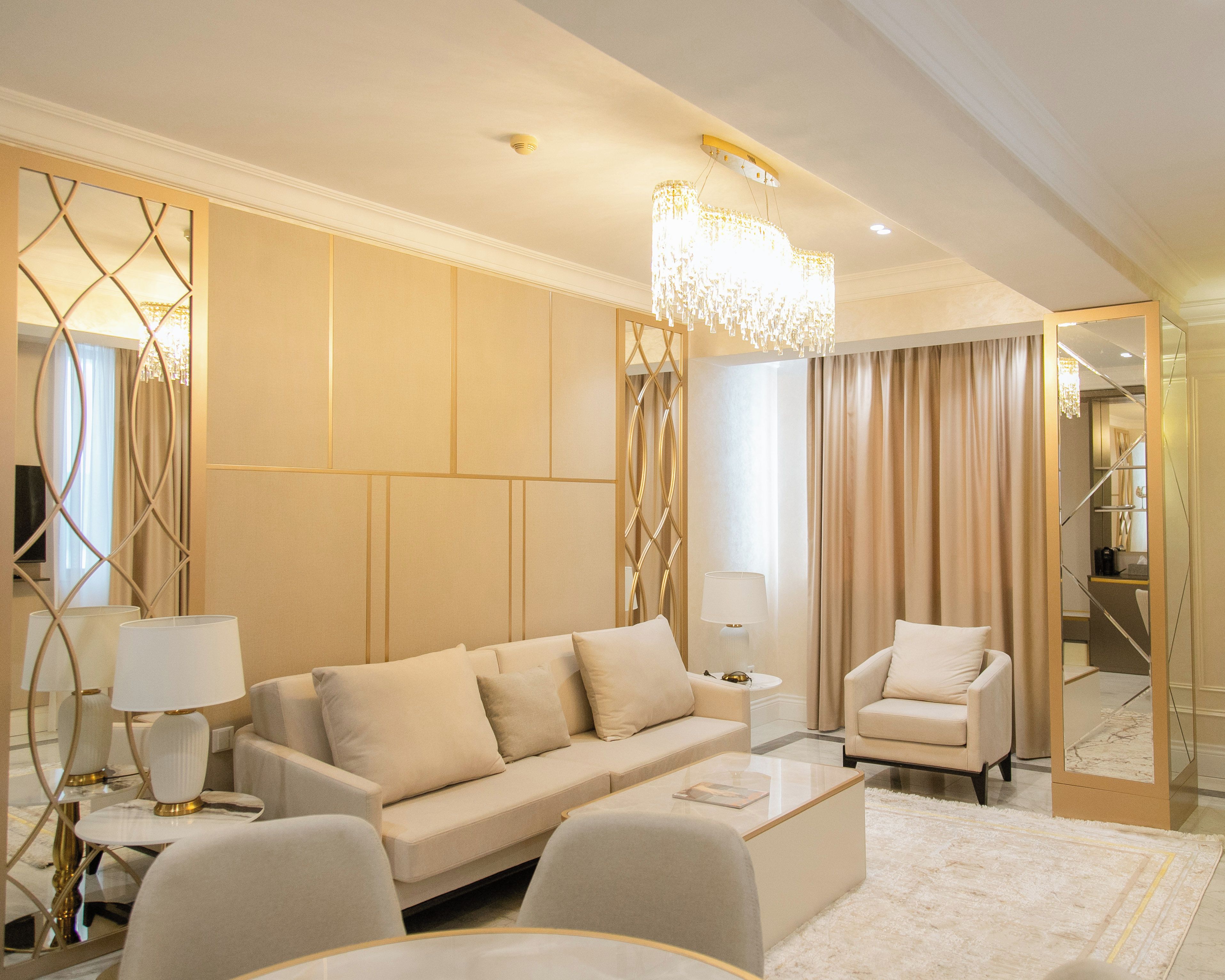 Una sala de estar moderna con un sofá, sillones, una mesa de centro y una araña.
