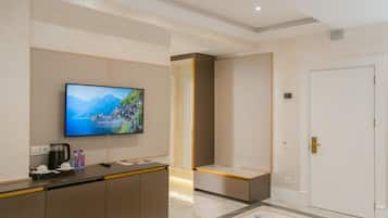 A hotel lobby with a reception desk, a television displaying a scenic view, a white door, and a marble floor.