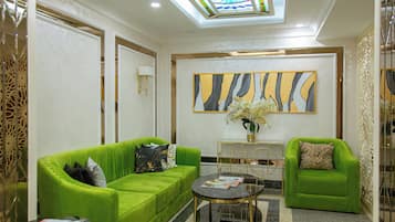 A modern living room with green sofas, a round coffee table, and a large abstract painting on the wall.