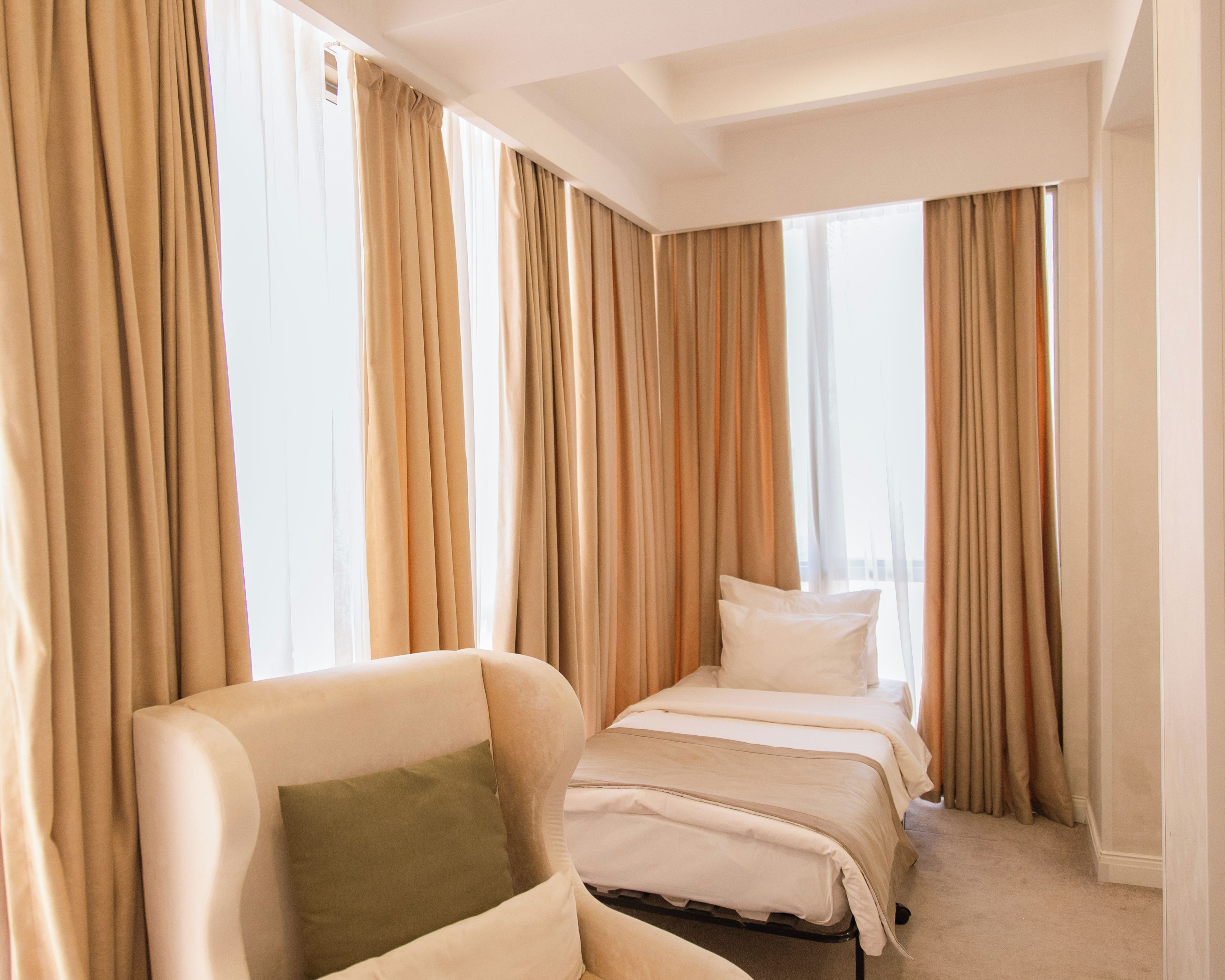 Una habitación de hotel con una cama individual, una silla y cortinas.