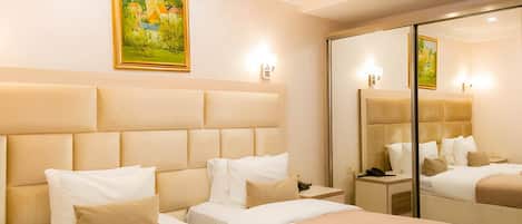 A hotel room with a large bed, a bedside table, a nightstand, a mirror, and a painting on the wall.