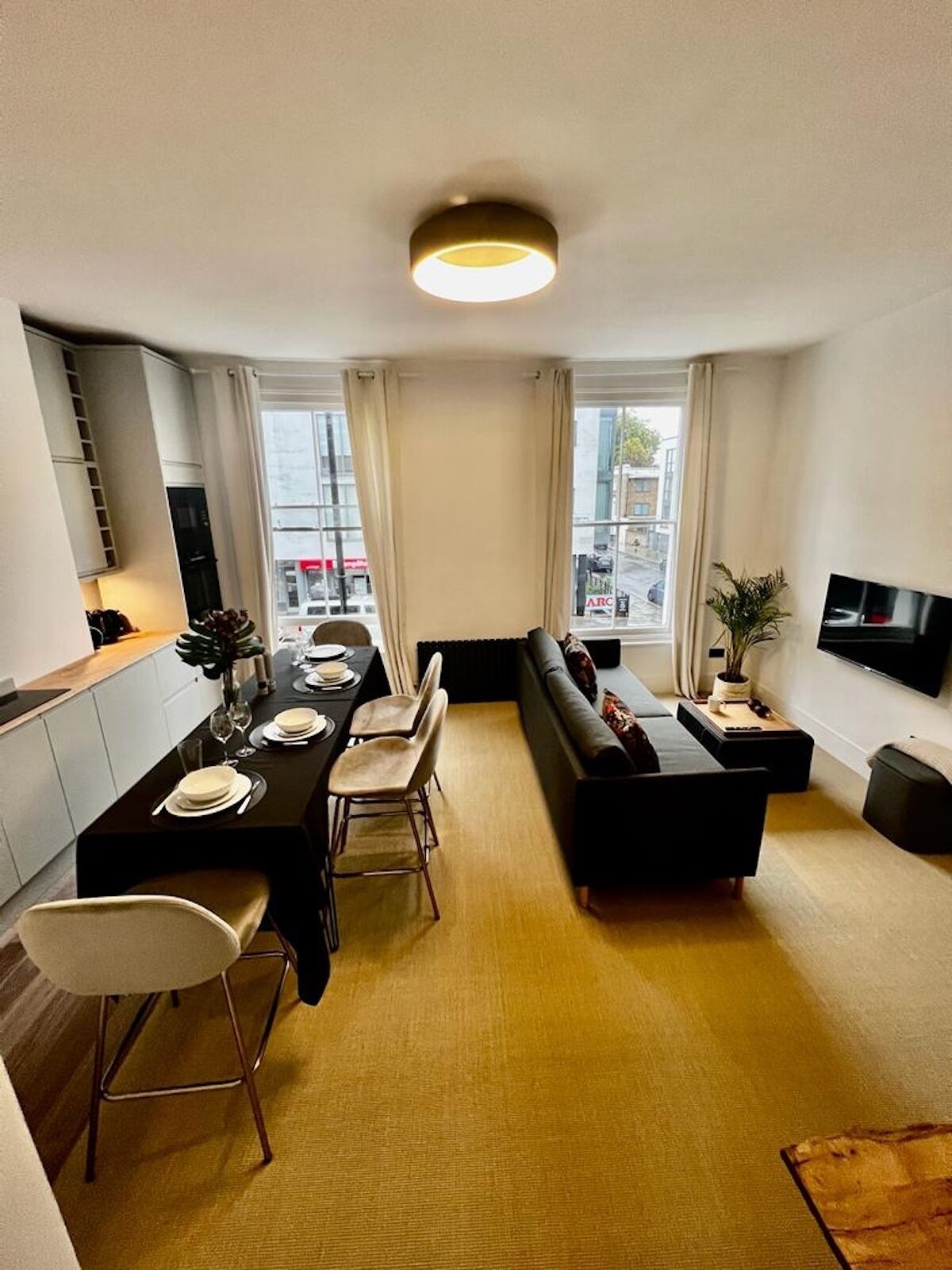 Ein modernes Wohnzimmer mit Essbereich, einer Couch und einem an der Wand befestigten Flachbildfernseher.
