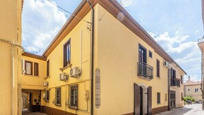 Um edifício amarelo com varanda, porta e janela.