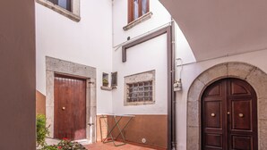 Um pátio com telhas de terracota, uma porta de madeira e um arco de pedra.
