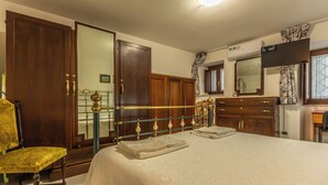 Quarto com cama, cadeira, guarda-roupa e espelho.