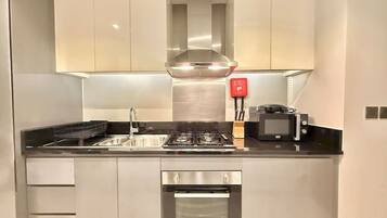 Una cocina compacta con una campana de acero inoxidable, horno integrado y microondas.
