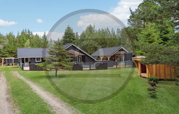 Een moderne lodge met twee huisjes, een overdekt terras en een verzorgd gazon.