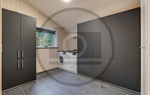 A laundry room with a washing machine, a dryer, and grey cabinets. - Beautiful home in Blåvand with sauna (Blåvand)