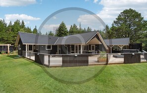 Een huis met twee verdiepingen, een overdekte patio en een omheinde tuin.
