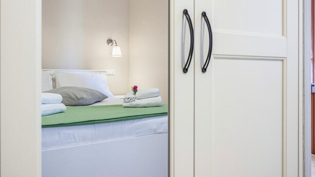 Ein Hotelzimmer mit Bett, Nachttisch, Lampe und Kleiderschrank.