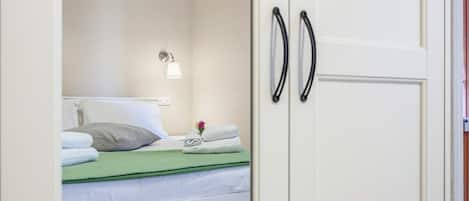 Ein Hotelzimmer mit Bett, Nachttisch, Lampe und Kleiderschrank.
