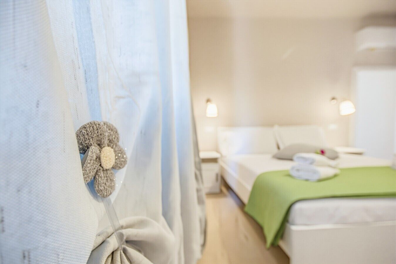 Ein Hotelzimmer mit einem Bett, einer grünen Decke und einem dekorativen Element am Vorhang.