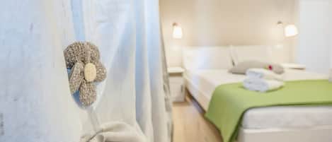 A hotel room with a bed, a green blanket, and a decorative item on the curtain.