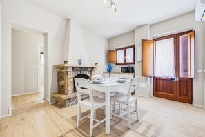 A dining area with a fireplace, white chairs, and a table set for four. - Rosa Giardino - Lavaiano (Lavaiano)