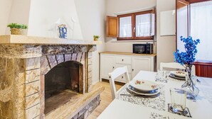 Eine Küche mit Steinofen, weißen Schränken, einer Mikrowelle und einem Esszimmertisch, gedeckt mit Tellern und Gläsern.