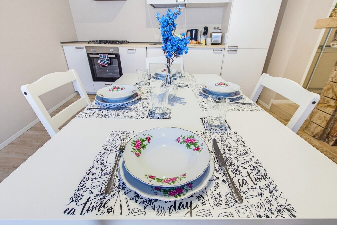 Un tavolo da pranzo apparecchiato con piatti, posate e un vaso con fiori blu.