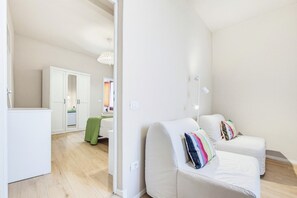 Un salon moderne et minimaliste, avec un canapé, un fauteuil vert et un miroir.