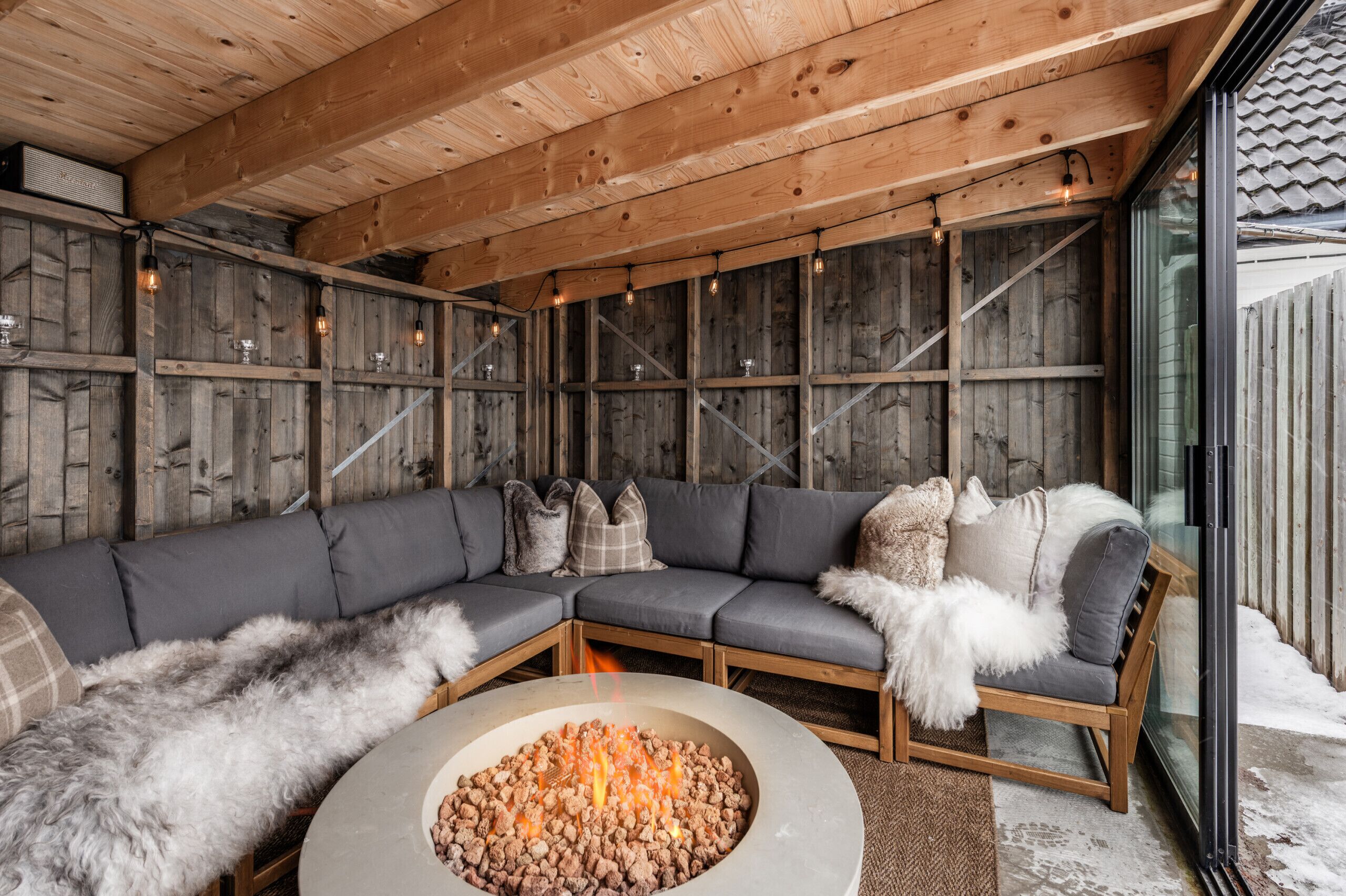 A cozy outdoor seating area with a built-in fire pit and a wooden ceiling.