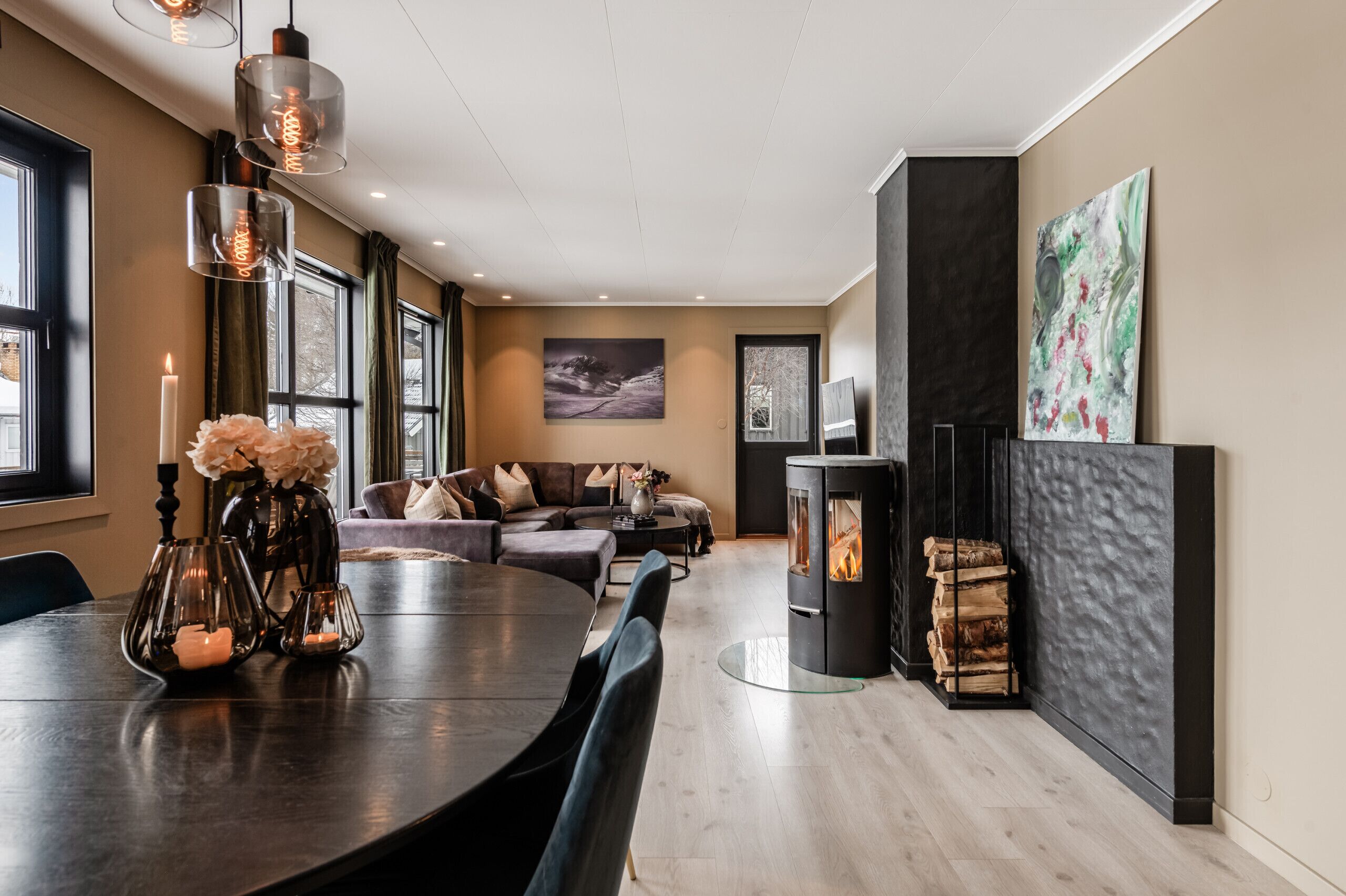 A modern living room with a fireplace, a dining table with chairs, and a sofa.
