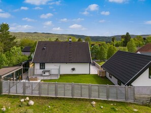 Een woonhuis met omheinde tuin, een losstaande garage en een woning met schuine dak.