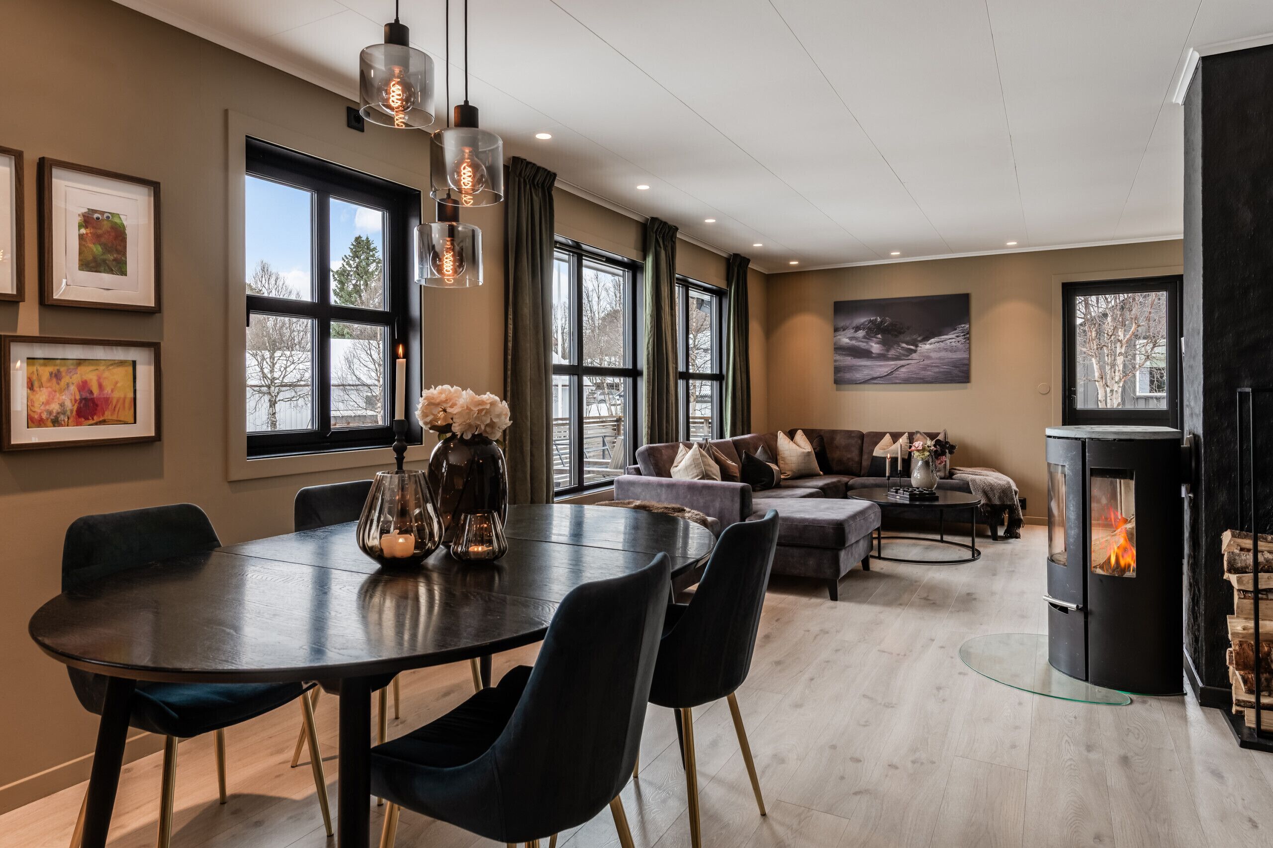 A modern living room with a fireplace, a dining area, and large windows.