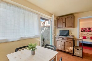 A room with a dining table, chairs, a television, a cabinet, and a bed with red pillows. - [IlGelsomino] Biassa-5Terre+A/C+ bus for 5 terre (Biassa)
