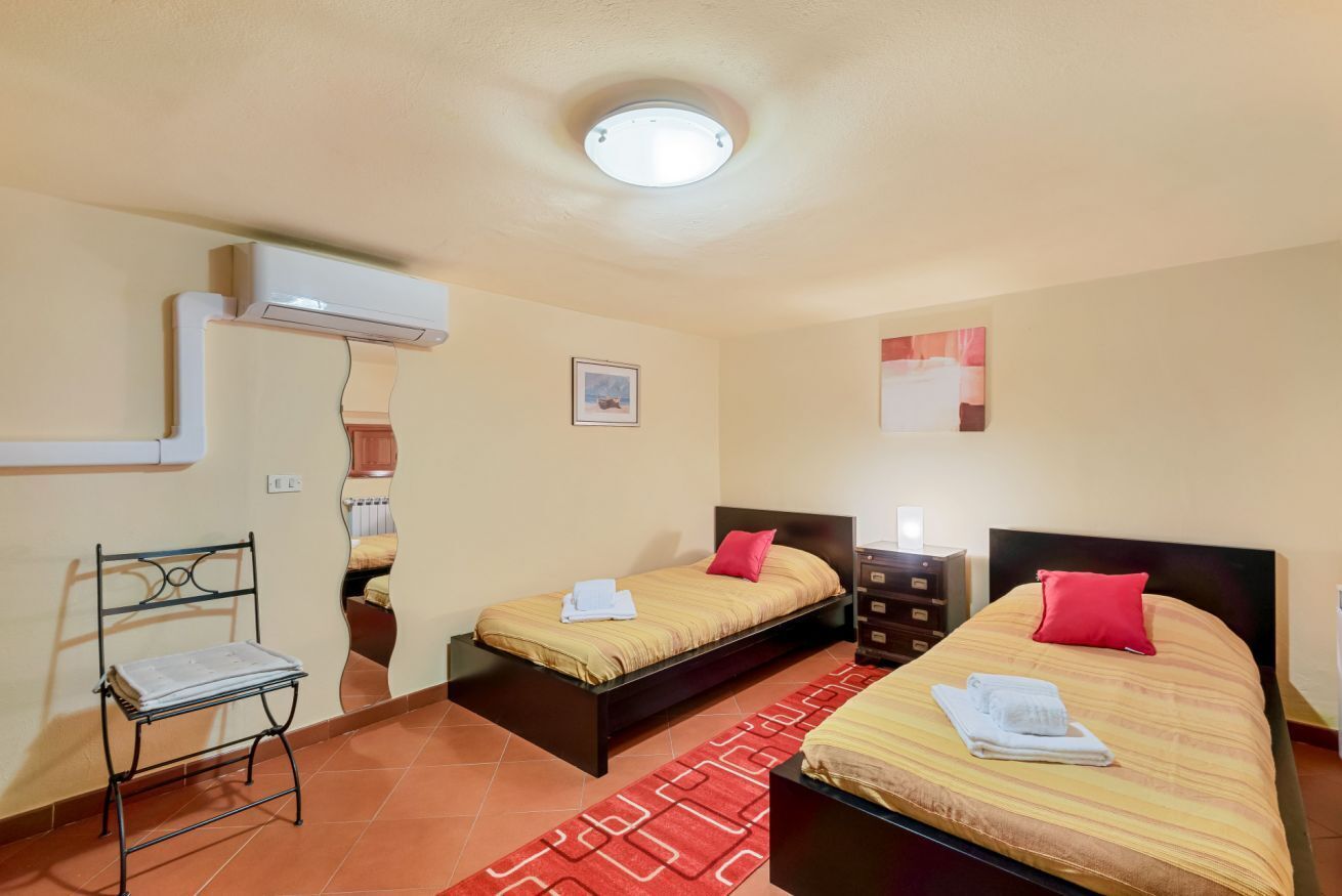 Habitación de hotel con dos camas, una silla, un aparador y un tapete rojo estampado.