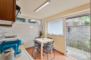 A compact kitchen with a dining area, a built-in stove, and a window with a view of a stone wall. - [IlGelsomino] Biassa-5Terre+A/C+ bus for 5 terre (Biassa)