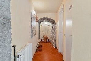 Un pasillo con un radiador, una pared de piedra y una puerta al final.