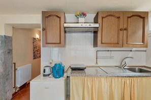 A compact kitchen with wooden cabinets, a built-in stove, a sink, and a small refrigerator. - [IlGelsomino] Biassa-5Terre+A/C+ bus for 5 terre (Biassa)