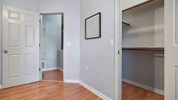 Un couloir avec une porte blanche, un tableau encadré au mur et une armoire avec une porte en bois.