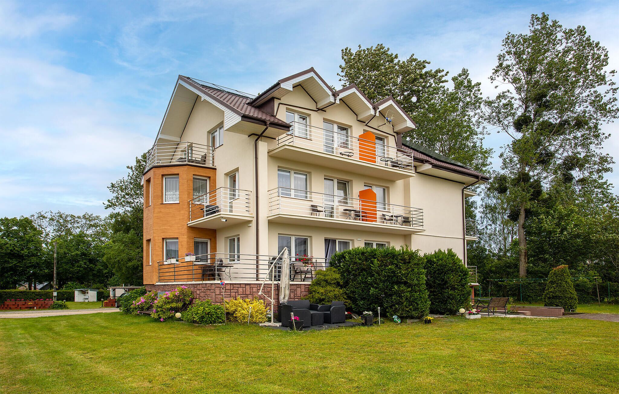 A multi-story residential building with balconies, a garden area, and outdoor furniture.