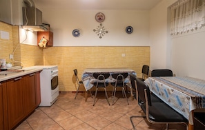 A compact kitchen with a dining area, featuring a stove, chairs, and a table with a patterned tablecloth. - Cozy apartment in Jastrzebia Gora with sauna (Jastrzebia Gora)