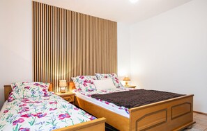 A bedroom with two wooden beds, each with floral bedding and a bedside lamp. - Cozy apartment in Jastrzebia Gora with sauna (Jastrzebia Gora)