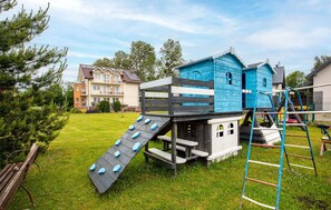 A playground with a slide and climbing structures, surrounded by a grassy yard and residential buildings. - Cozy apartment in Jastrzebia Gora with sauna (Jastrzebia Gora)