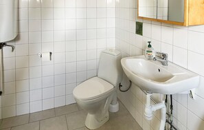 Un baño con inodoro, lavamanos y espejo sobre él.