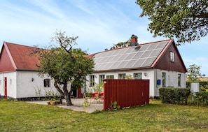 Ein Haus mit rotem Dach, weißen Wänden und Solaranlage auf dem Dach.