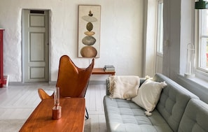 A living room with a wooden table, a leather chair, a grey sofa, and a painting on the wall. - Awesome home in Tomelilla with WiFi (Tomelilla)