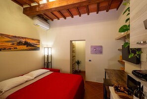 Ein Schlafzimmer mit einem roten Bett, einem Bild an der Wand, einer Nachttischlampe und einem Schild mit der Aufschrift 'HOME'.