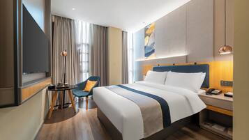 A hotel room with a large bed, a desk with a phone, a chair, and a TV.