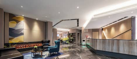 A modern lobby with a reception desk, seating area, and a decorative wall.